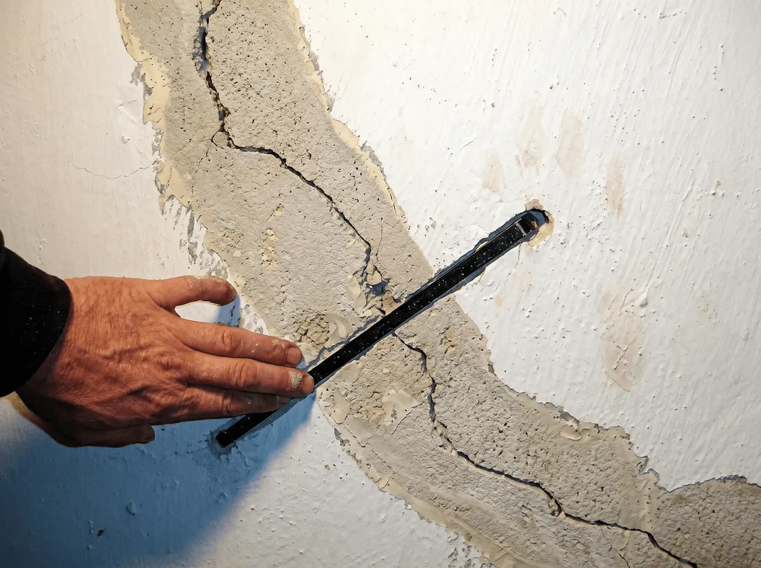 A wall with a large crack is being inspected by a professional in Eugene, OR